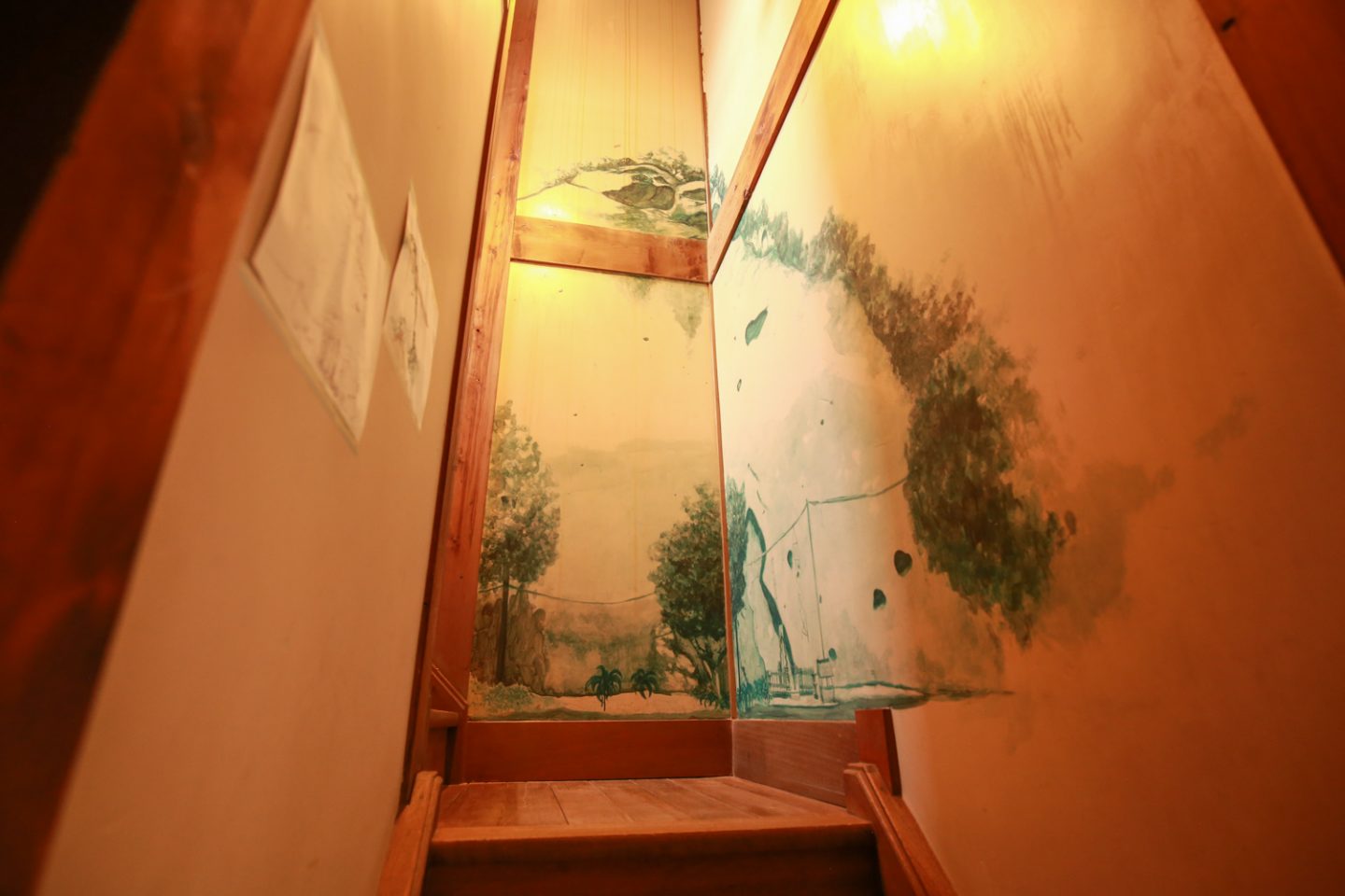 ▲２階に続く階段の壁には、井上さんの友人が描いた「花の窟」の絵が現れる